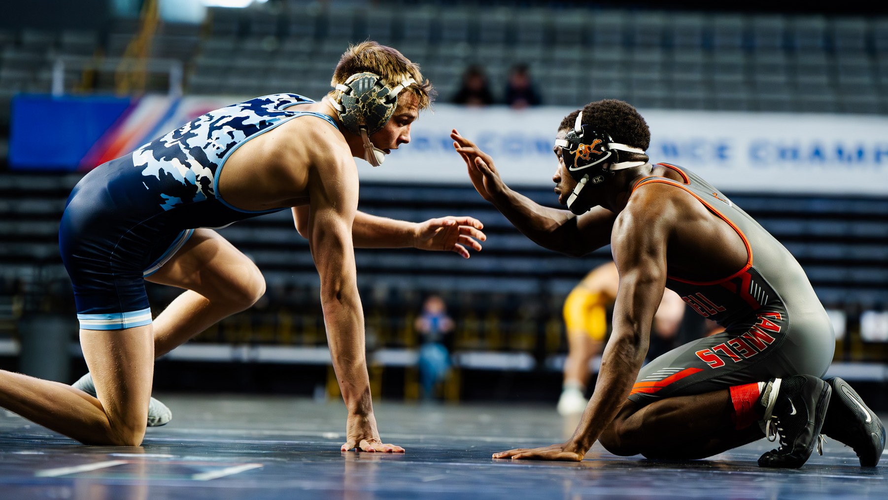Sports photography of two college wrestlers facing off at a championship match