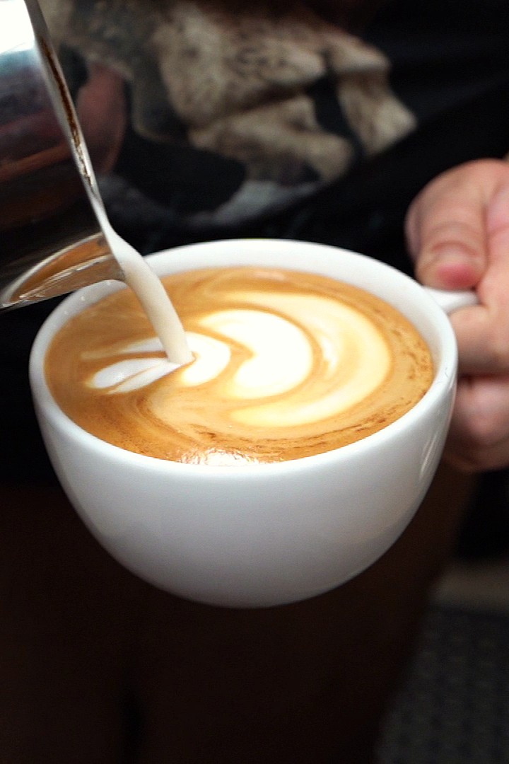 Commercial brand photography of a barista pouring latte art at a coffee shop in the Triangle, NC