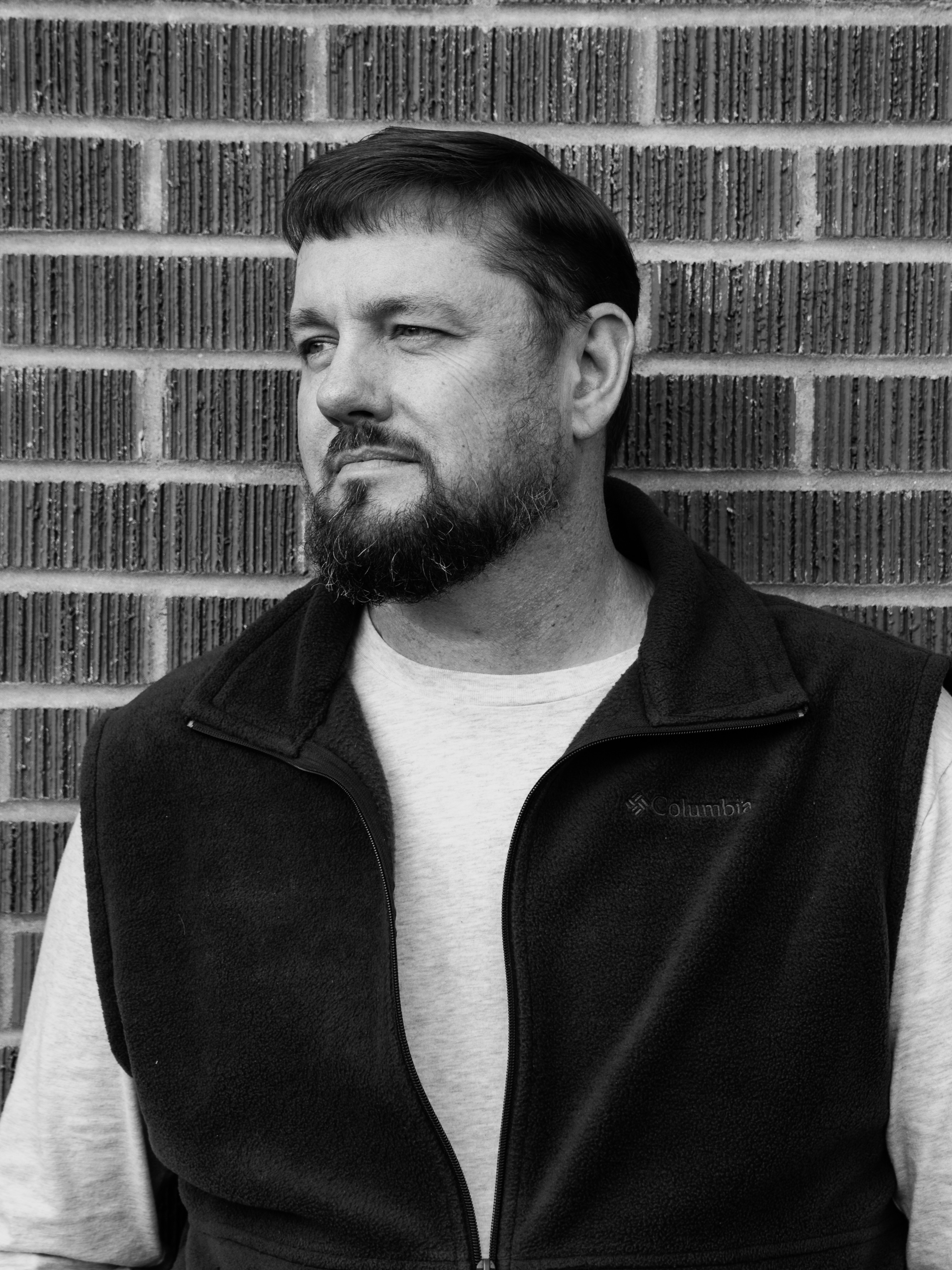 Professional black-and-white headshot of a man against a brick wall
