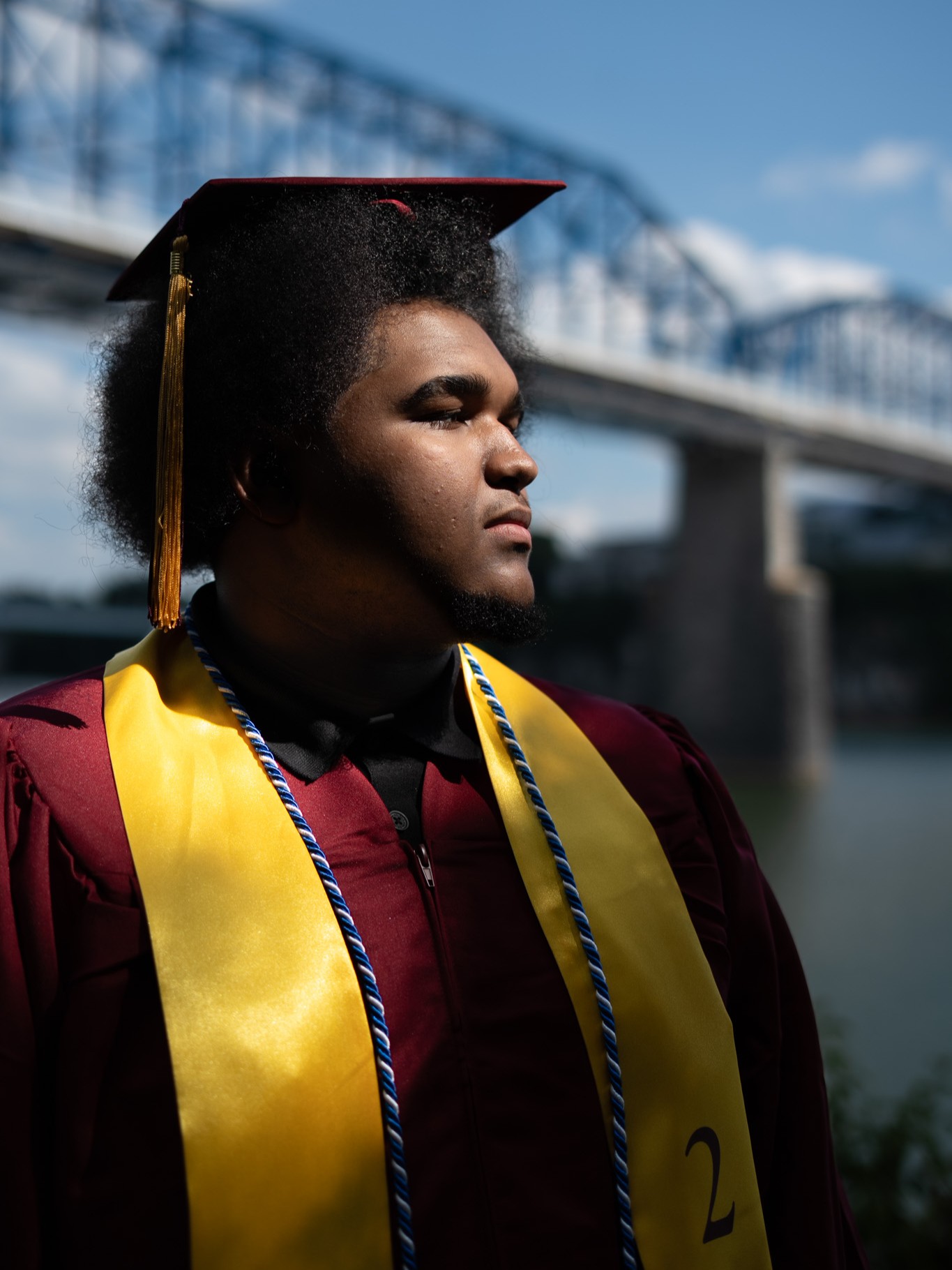 Senior graduation portrait of a graduate by a river and bridge