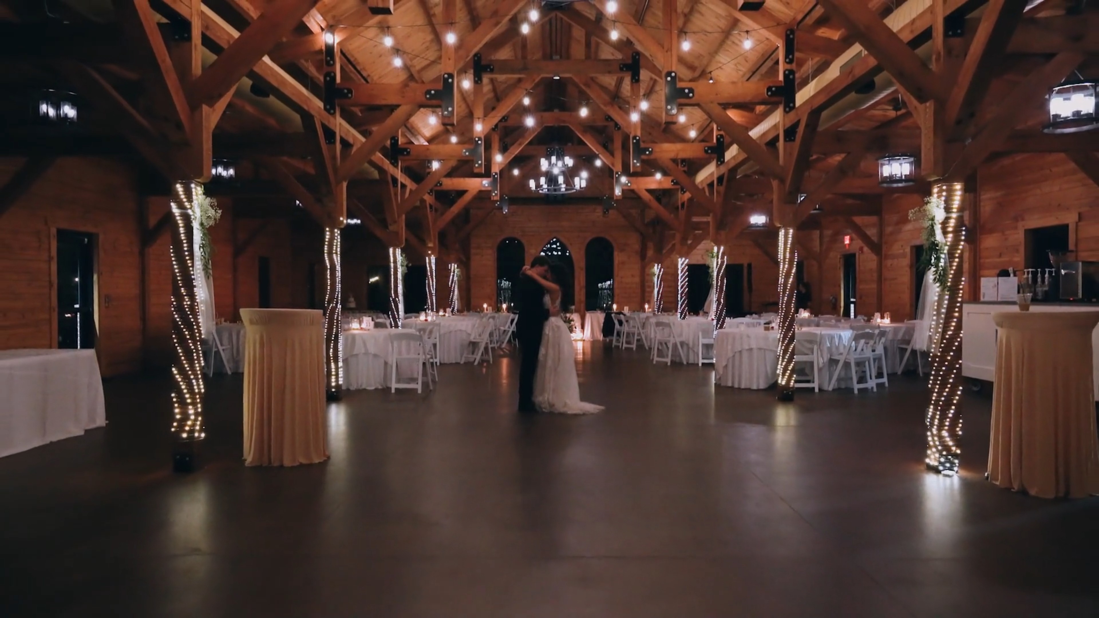 Bride and groom's first dance at a barn wedding reception with string lights